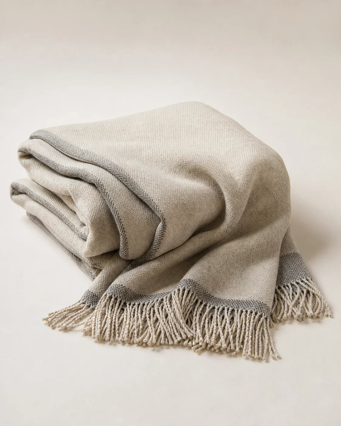 Pass Yak-Wool Travel Throw by ALPORA, a soft, lightweight travel layer in natural oatmeal with a smoke-grey handwoven border